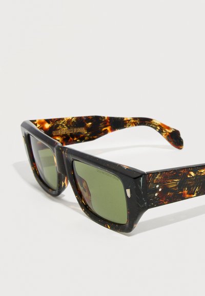 Occhiali da sole rettangolari con montatura tartarugata, lenti verde scuro, aste spesse e motivo maculato ambra e nero sulle aste.
