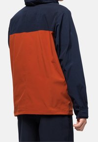 Jacka med en övre del i marinblått och en nedre del i orange. Tillverkad av slätt tyg, inkluderar huva och elastiska ärmslut.