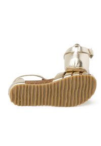 Sandal in metallo dorato con fondo in sughero, cinturino alla caviglia regolabile e suola in gomma rigata per una migliore aderenza. Caratterizza un design e una forma minimalista.