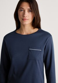Marineblauw langemouwen shirt van zachte stof, met een borstzak met een witte bies, ronde hals en een relaxte pasvorm.