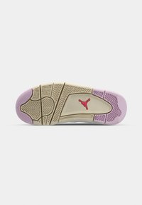 Semelle d'une basket beige et lavande avec des grips texturés et un logo Jumpman rouge au centre sur un fond blanc.
