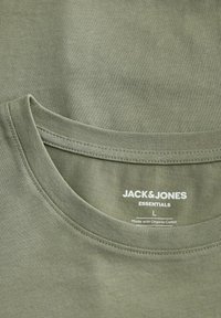 Green organic cotton T-shirt, featuring a crew neck, soft texture, and label with "JACK & JONES ESSENTIALS" in white. Size L.
