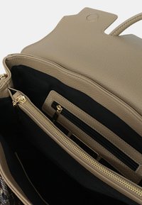Borsa a mano in pelle beige con finitura testurizzata. Presenta un interno nero e molteplici tasche, tra cui un comparto con cerniera e dettagli dorati.
