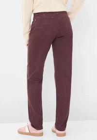 Pantaloni dritti bordeaux con tasche laterali e tasche posteriori, realizzati in morbido cotone misto, abbinati a sneaker rosa chiaro.