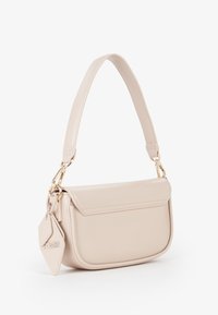 Borsa a spalla piccola beige con una tracolla ampia, chiusura a patta e un'etichetta a forma di diamante attaccata a un lato con dettagli in oro.