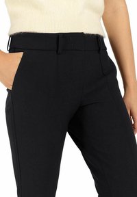Pantalones de corte recto en negro con una textura suave, que presentan una cintura con cinturón, bolsillos laterales y costuras frontales. La tela muestra elasticidad y durabilidad.