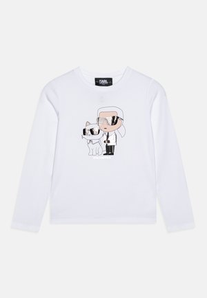 Sweatshirt à manches longues blanc avec un graphique de dessin animé représentant une personne et un chat, tous deux portant des lunettes de soleil réfléchissantes et des détails en contours.