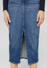 Modrá džínsová sukně se rovný střih, délka ke kolenům, s předním rozparkem a viditelnými švy. Klasický design s pěti kapsami.