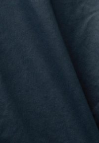 Ciemnoniebieska tkanina o gładkiej fakturze, z delikatnym połyskiem i drobnym wzorem tkania, złożona tak, aby ukazać głębię i kontury.