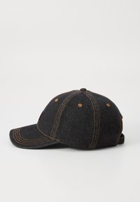 Casquette de baseball en denim foncé avec des coutures orange et une visière courbée. Design à six panneaux avec des œillets de ventilation et une sangle ajustable.