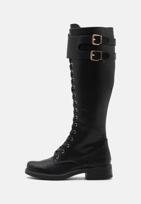 Knee-high black leather boots with gold hardware accents, featuring a lace-up front, two buckle straps, and a block heel.