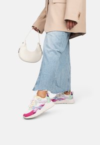 Colorful sneakers with mesh and suede details in white, pink, green, and purple; paired with a light blue denim skirt and beige blazer.