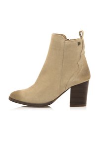 Stivaletto in suede beige con punta a mandorla, dettagli a scallop e tacco in legno impilato. Chiusura con zip sul retro per una maggiore facilità.