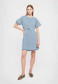 Τζιν φόρεμα σε ανοιχτό μπλε χρώμα, με κοντά μανίκια, στρογγυλή λαιμόκοψη και ζωνάκι στη μέση; διαθέτει άνετη εφαρμογή με στρίφωμα πάνω από το γόνατο.