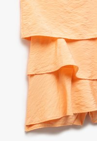 Textil en tono durazno, con capas y una superficie texturizada. El diseño presenta suaves volantes y un dobladillo que se curva suavemente.