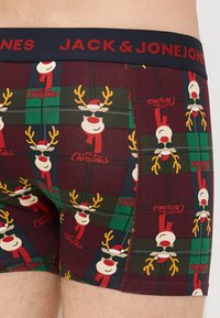 Boxer shorts made of stretchy fabric, featuring a festive reindeer pattern on a burgundy background with green and plaid accents.