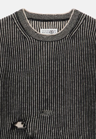 Maglione a costine nero e beige con scollatura a girocollo, caratterizzato da righe verticali e un piccolo foro decorativo sul corpo.