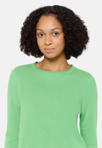 Pull col rond vert clair en tissu doux et texturé ; manches longues et coupe décontractée ; pas de motifs ou accents visibles.