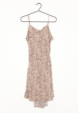 Vestido midi sin mangas con tirantes finos, fondo beige y patrón de puntos irregulares negros, colgado en una percha negra.