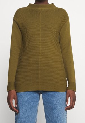 Olive green, textured knit sweater with a high neck and dropped shoulders. Features long sleeves and a relaxed fit. Worn over light blue jeans.