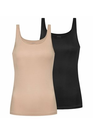 Frau mit geflochtenem Haar, die ein schwarzes Tanktop und schwarze Unterwäsche trägt, steht vor einem schlichten hellen Hintergrund.