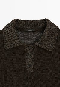 Brun stickad polo med en texturerad krage, tre mörka knappar och ett fint nätmönster på kroppen, märkt "Massimo Dutti".