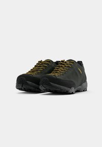 Green hiking shoes with black accents, sturdy rubber soles, textured laces, and reinforced toe caps for enhanced durability.