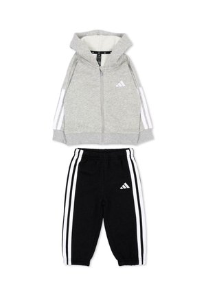 Survêtement enfant deux pièces avec veste à capuche grise zippée et pantalon noir, les deux avec des bandes blanches et le logo Adidas sur chaque pièce.