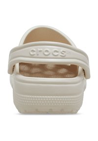 White Crocs with a textured footbed and solid heel strap. The sole features small raised dots for grip. No patterns or embellishments present.