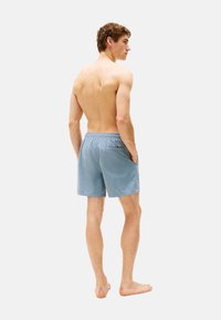 Bañador ligero para hombres en color azul claro, con cintura elástica, bolsillos laterales y un bolsillo trasero con un pequeño detalle de logo.