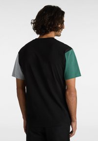 Kortärmad t-shirt med färgblockdesign som har svarta, grå och teal-sektioner. Tillverkad av bomull med en mjuk textur.