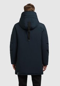 Parka imbottita blu navy con colletto alto, cappuccio regolabile e tasche laterali. Caratterizzato da un design elegante e una texture liscia.