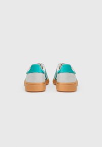 Sneakers med en lys grå overdel, teal accenter og en struktureret brun gummisål. Lukket bagdesign med kontrastfarvede detaljer.