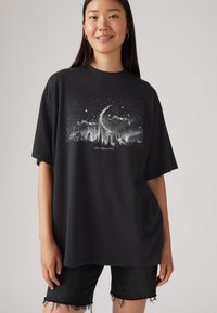 Sort oversized T-shirt med grafik af en stjerneklar himmel og skov i hvid, med korte ærmer og en afslappet pasform.