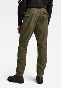 Olivgröna cargo-byxor med rak passform, featuring två stora bakt pockets, pinstripe-textur och kombinerat med svarta ankelstövlar.