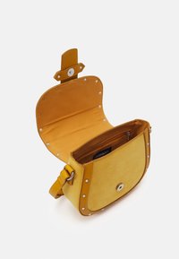 Borsa gialla con texture scamosciata, forma circolare, chiusura a scatto e borchie argentate lungo i bordi. Interno foderato in tessuto abbinato.