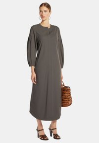 Lungo abito grigio con colletto alto, maniche a sbuffo e taglio dritto. Abbinato a una borsa intrecciata marrone e tacchi neri con fascette.