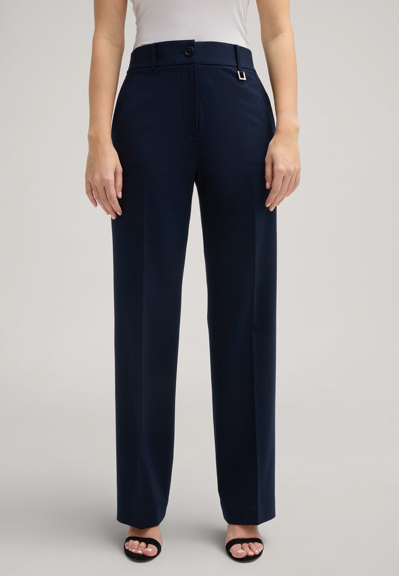 Marineblaue Hose aus glattem Stoff, mit taillierter Passform, einem einzelnen Knopfverschluss und einem dezenten metallischen Akzent am Bund.