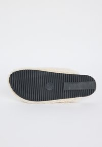Sole di una pantofole color crema con suola in gomma nera a costine e la marcatura della taglia 38/39 visibile al centro.