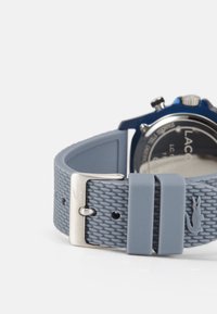 Reloj deportivo azul con una correa de silicona gris texturizada, hebilla de acero inoxidable y un dial circular con múltiples botones de función.