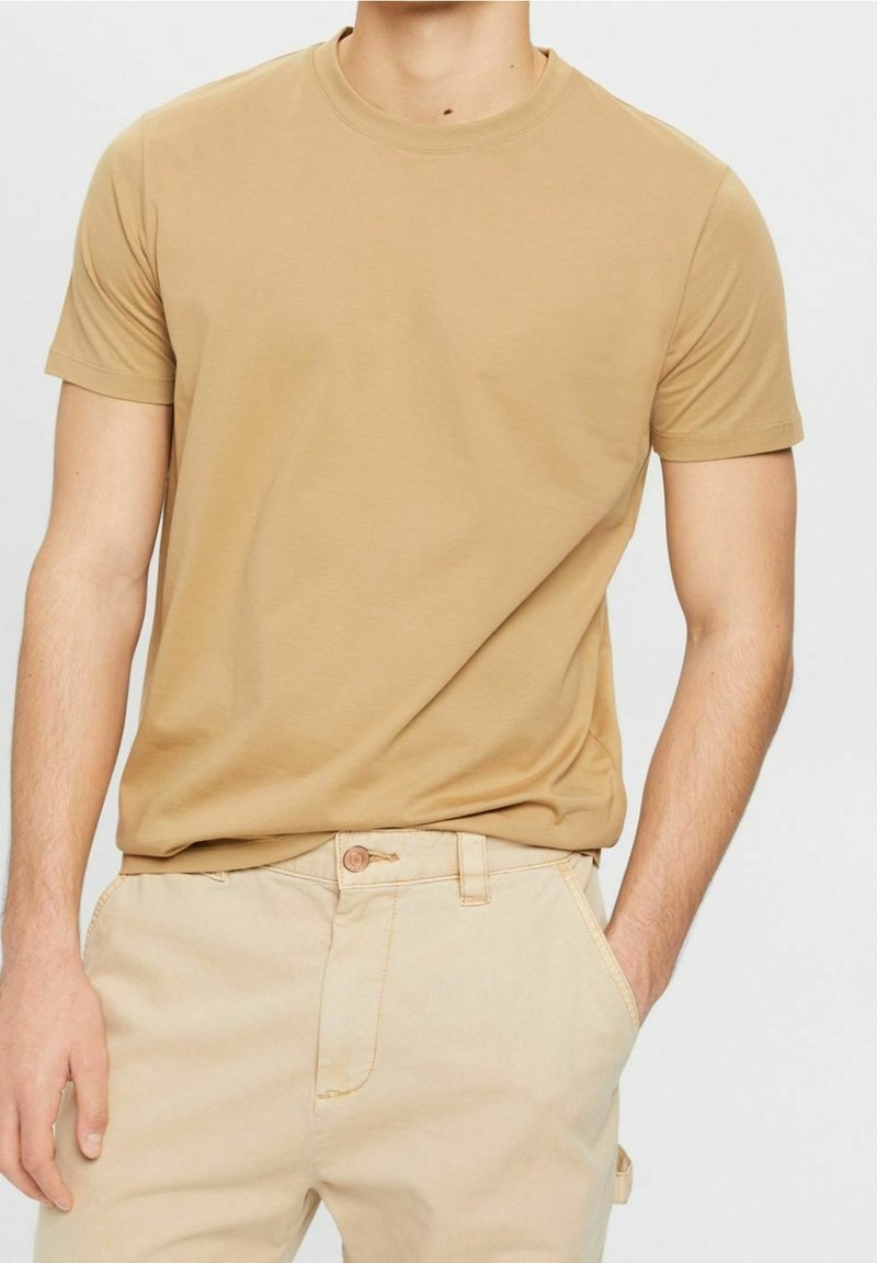 T-shirt kaki à col rond en tissu doux en mélange de coton. Manches courtes, coupe près du corps, design minimaliste sans graphismes ni ornements.
