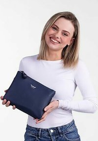 Tmavě modrá taštička vyrobená z hladkého materiálu, s nenápadným logem, zipovým uzávěrem a poutkem na ruku. Obdélníkový tvar, kompaktní velikost.