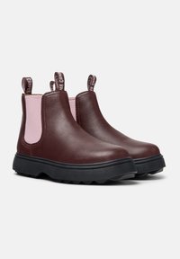 Bottines en cuir marron avec des panneaux élastiques latéraux roses, bout rond et semelle en caoutchouc noir avec un motif de traction. Onglets de traction pour un enfilage facile.
