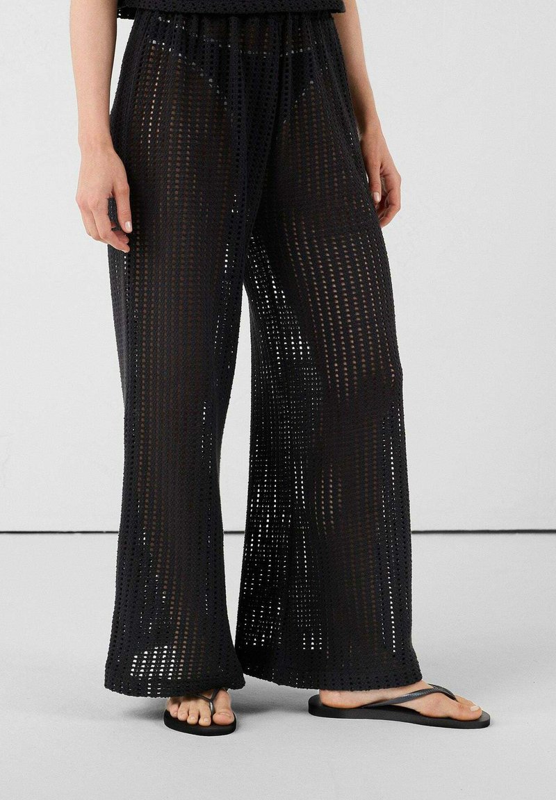 Pantalones de punto negros, ligeros, de tejido suelto, con piernas anchas y una cinturilla elástica, con un diseño transparente y corte recto.