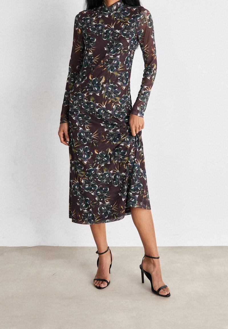 Robe à manches longues imprimée de fleurs en marron foncé et vert, avec une coupe ajustée et une longueur intermédiaire. Assortie avec des sandales à talons hauts noires.