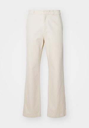 Calças beige de algodão com um design de perna reta, apresentando um fecho frontal com zíper e botão, textura suave e estilo minimalista.