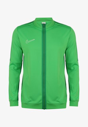 Grøn Nike sportssweatshirt med fuld lynlås, lange ærmer, sidelommer, ribstrikkede manchetter og et hvidt Nike-logo på venstre bryst.