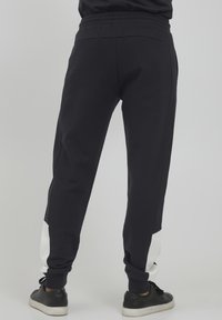 Navy joggebukser i bomull-blanding, med hvite sidepaneler, elastisk midje og ribbede ankler. Glatt tekstur, enkelt design.