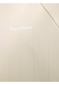 Beige tekstureret stof med lodrette striber; har broderet "ProjectCore" logo i hvid. Enkel, strømlinet design.