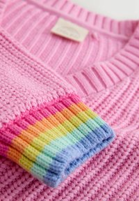Rózsaszín kötött pulóver bordázott gallérral és többszínű csíkos mandzsettákkal, vörös, narancs, sárga, zöld, kék és lila árnyalatokkal.